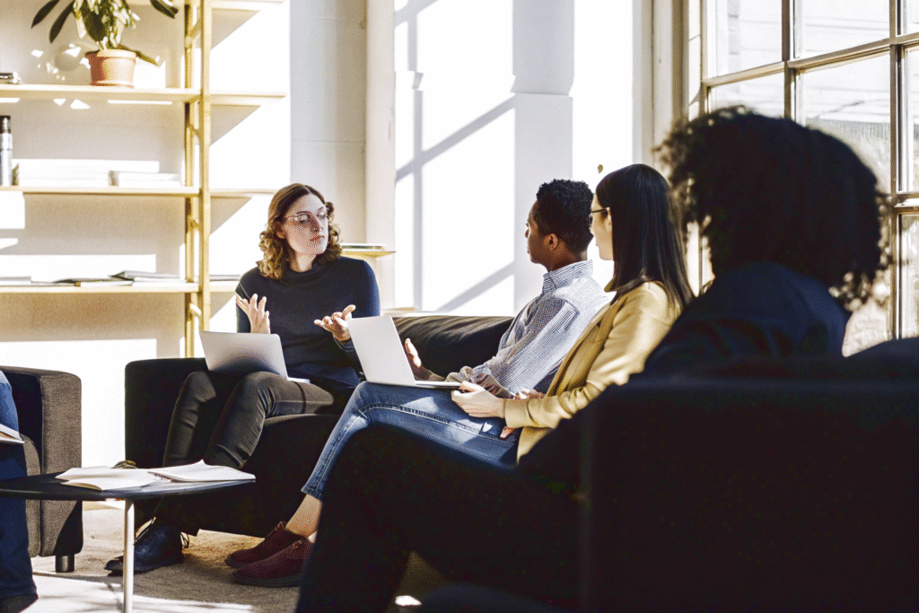 A team of experts discusses the project, sitting with laptops by the window in a cozy modern office.